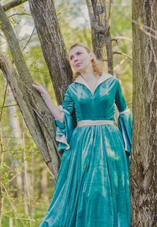 Portrait of a young girl in a green dress in the form of a forest nymph in the woodsの写真素材