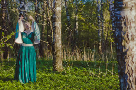 Portrait of a young girl in a green dress in the form of a forest nymph in the woodsの写真素材