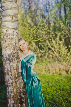 Portrait of a young girl in a green dress in the form of a forest nymph in the woodsの写真素材