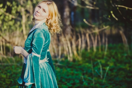 Portrait of a young girl in a green dress in the form of a forest nymph in the woods