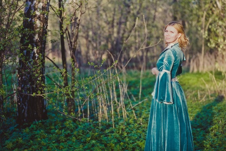 Portrait of a young girl in a green dress in the form of a forest nymph in the woodsの写真素材