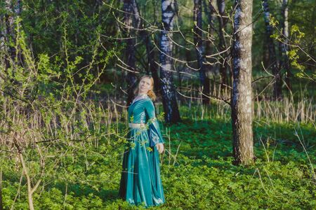 Portrait of a young girl in a green dress in the form of a forest nymph in the woodsの写真素材