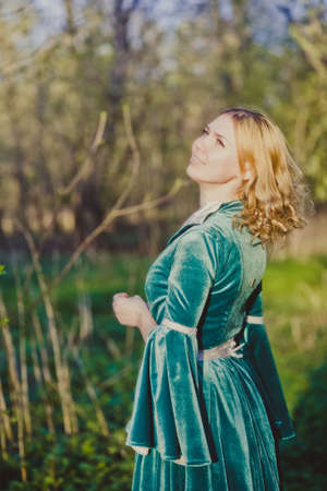 Portrait of a young girl in a green dress in the form of a forest nymph in the woodsの写真素材