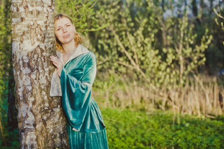 Portrait of a young girl in a green dress in the form of a forest nymph in the woodsの写真素材