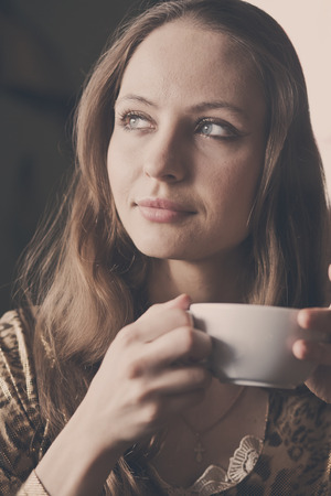 A young beautiful girl with a cup of tea, cappuccino toningの写真素材
