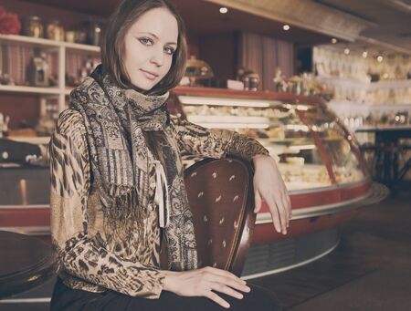 A young beautiful girl waiting for a cup of tea in a cafe, cappuccino toningの写真素材