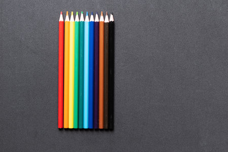 A rainbow of colored pencils, on a dark background.の写真素材