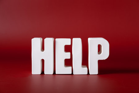 Word Help made from white concrete letters on the red background.