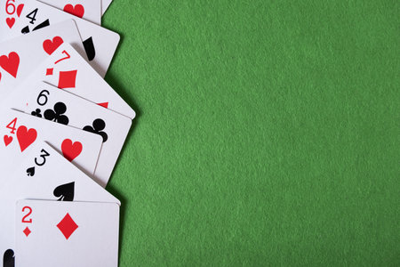 Playing cards on a green background with space for text.