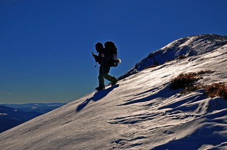 The tourist on a snow hillside in a winter landscape with the dark blue sky. の写真素材