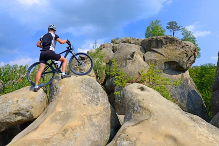 The man with the bike on the steep cliffs の写真素材