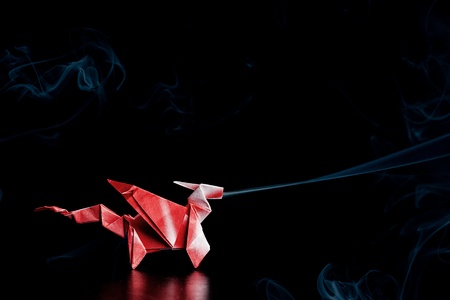 Red and white origami dragon billows smoke from its nose in this surreal and sleek imageの写真素材