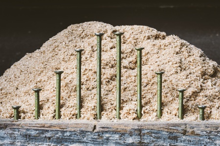 Geometric arrangement of sixteen-penny framing nails against a sawdust background