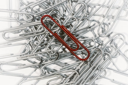 Lone red paper clip uniquely presented amongst others