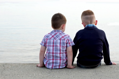 two btothers sitting on a beach wallの写真素材