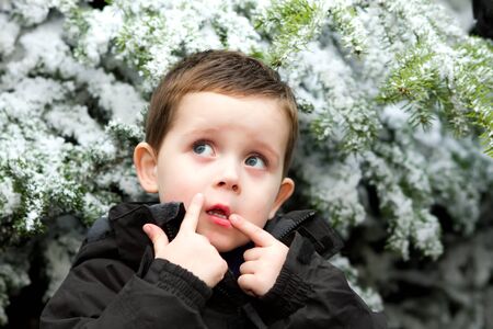a cute little boy in front of a snow covered treeの写真素材