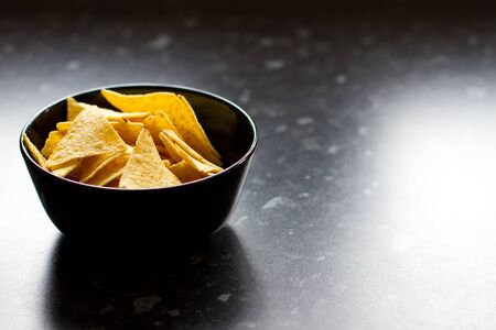 bowl of tortilla chips on a black kitchen counterの写真素材