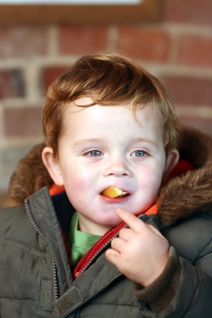 blue eyed boy eating a chip outdoorsの写真素材