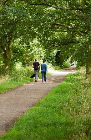 young couple walking their dog along a country pathの写真素材