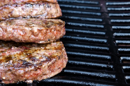 Beef quarterpounder burgers begin to cook on the gas barbecueの写真素材