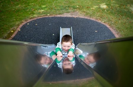 little boy sliding down a side at the parkの写真素材
