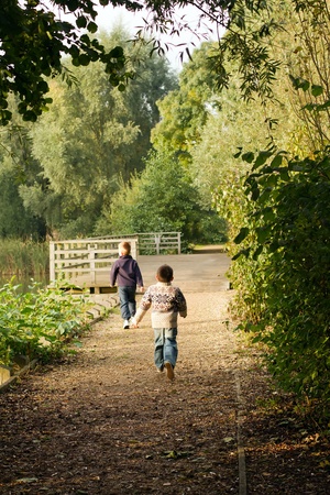 Brothers running near a pond in Autumnの写真素材