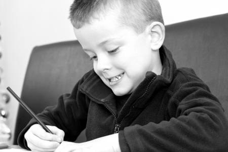 young boy drawing with pencils on a tableの写真素材