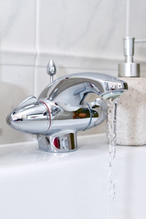 chrome bathroom tap with water runningの写真素材
