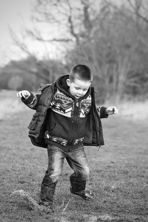 little boy splashing in a puddle in the fieldの写真素材