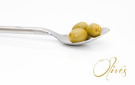 green olives upon a silver spoon isolatedの写真素材
