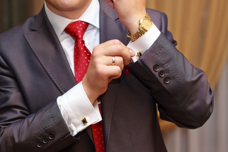 Close up of businessman with red tie and golden watch.