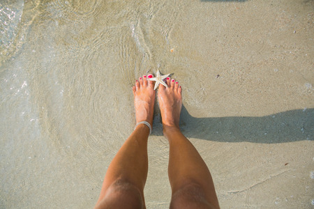 Human feet on the wet sand with a starfish の写真素材