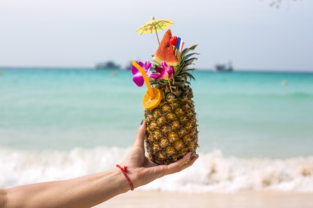 Pineapple coctail in a woman s hand infront of the sea の写真素材