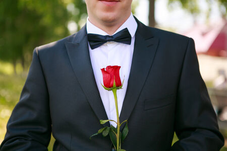 Groom with a bow tie and red roseの写真素材