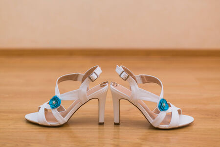 Close up of bride's shoes with blue flower and gold ringsの写真素材