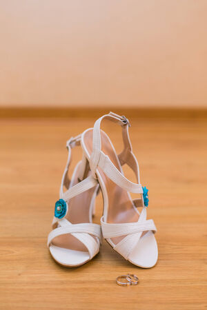 Close up of bride's shoes with blue flower and gold wedding ringsの写真素材