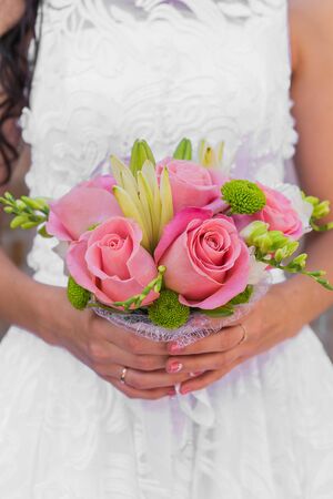 Wedding bouquet of pink roses and leaves in the brides handsの写真素材