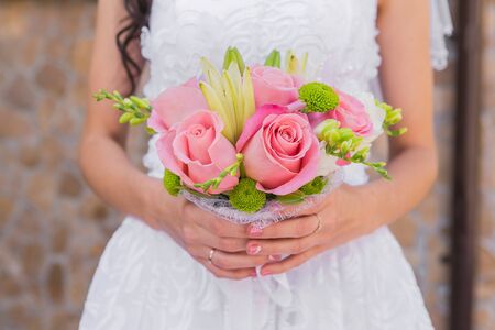 Wedding bouquet of pink roses and leaves in the brides handsの写真素材