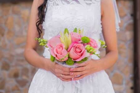 Wedding bouquet of pink roses and leaves in the brides handsの写真素材