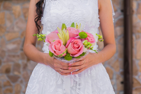 Wedding bouquet of pink roses and leaves in the brides handsの写真素材