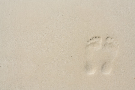 Footprint on the wet yellow sand next to the seaの写真素材