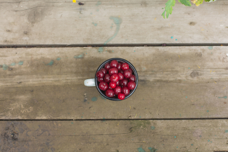 Fresh cherries in an old iron cup on a wooden tableの写真素材