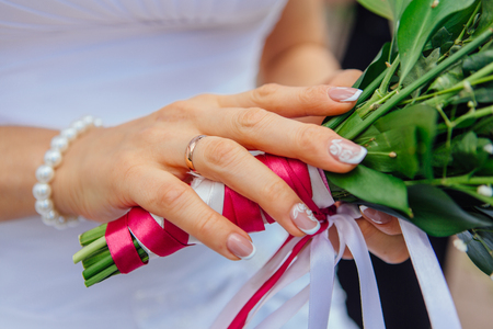 Wedding bouquet in the bride's hand with a ring on the finger.の写真素材