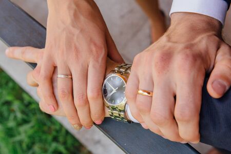 Hands of a man and a woman with wedding rings on the mans's wrist with watchの写真素材