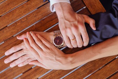Hands of a man and a woman with wedding rings on the mans's wrist with watchの写真素材