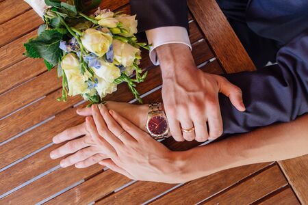 Hands of a man and a woman with wedding rings on the mans's wrist with watchの写真素材