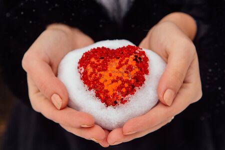 Woman holding red heart covered with snowの写真素材