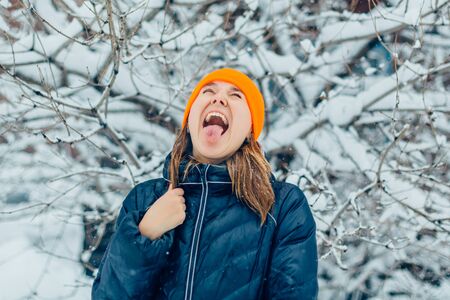 Portrait of a  young woman in warm clothes outdoor catching snowflakes.の写真素材