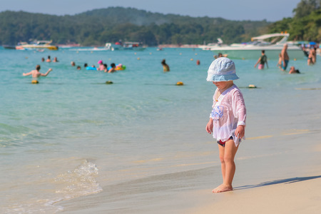 Koh Samed, Rayong, Thailand - December 25, 2014 :: Little kid in white hat playing on the beach near blue seaのeditorial素材