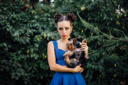 Young beautiful woman with Yorkshire Terrier near green bushの写真素材